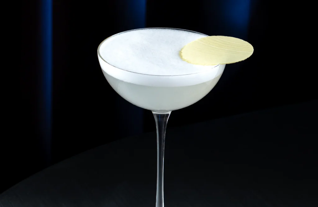 Cóctel Salt Air Margarita con 1800 Blanco servido en copa coupe, coronado con espuma de sal y decorado con una oblea.