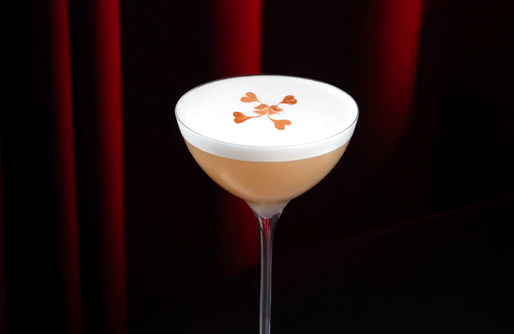 Cóctel GG de tequila con jerez servido en copa coupe con espuma de aquafaba y gotas de angostura.